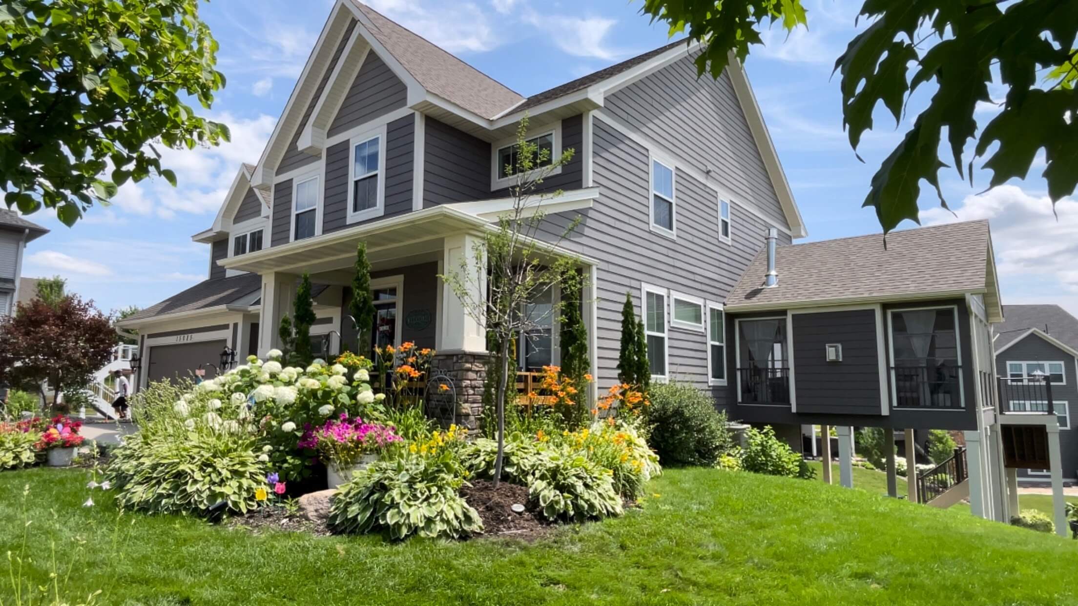 Well-maintained front yard featuring vibrant flower beds with annual flowers and nicely manicured grass.